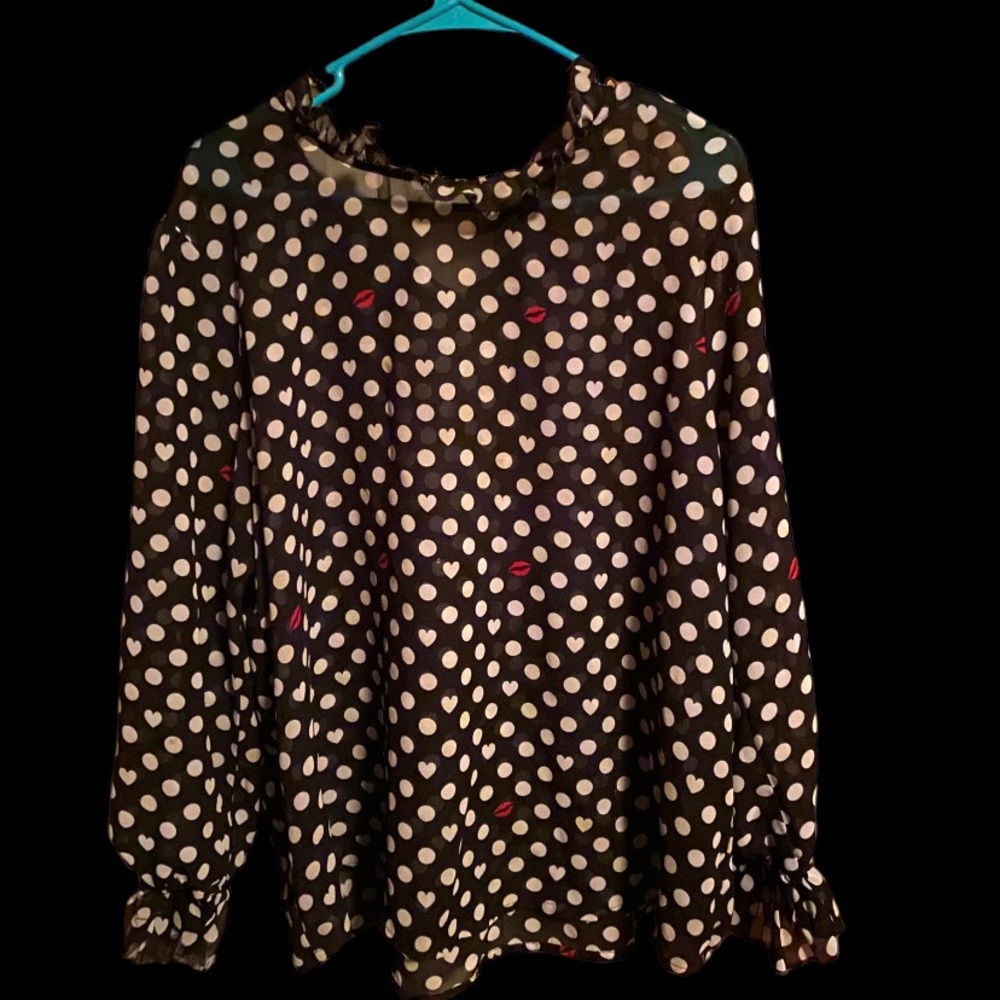 Black and white polkadot, blouse with printed red lips on it and with ruffles.